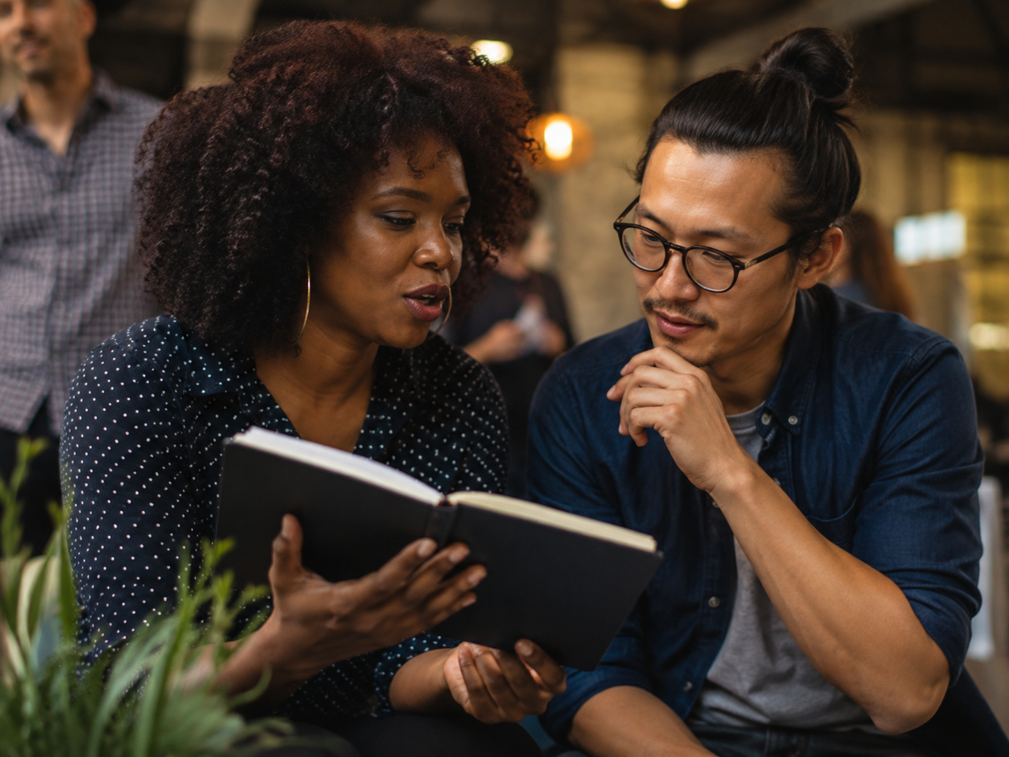 Adults discussing a notebook at a neighborhood tech meetup
