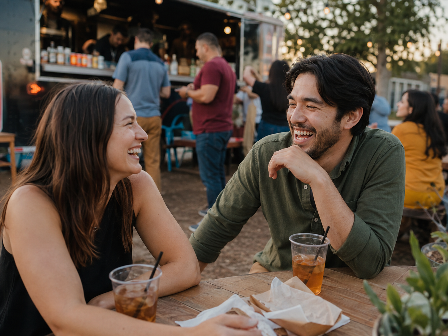 Adults laughing at an outdoor food-truck seating area