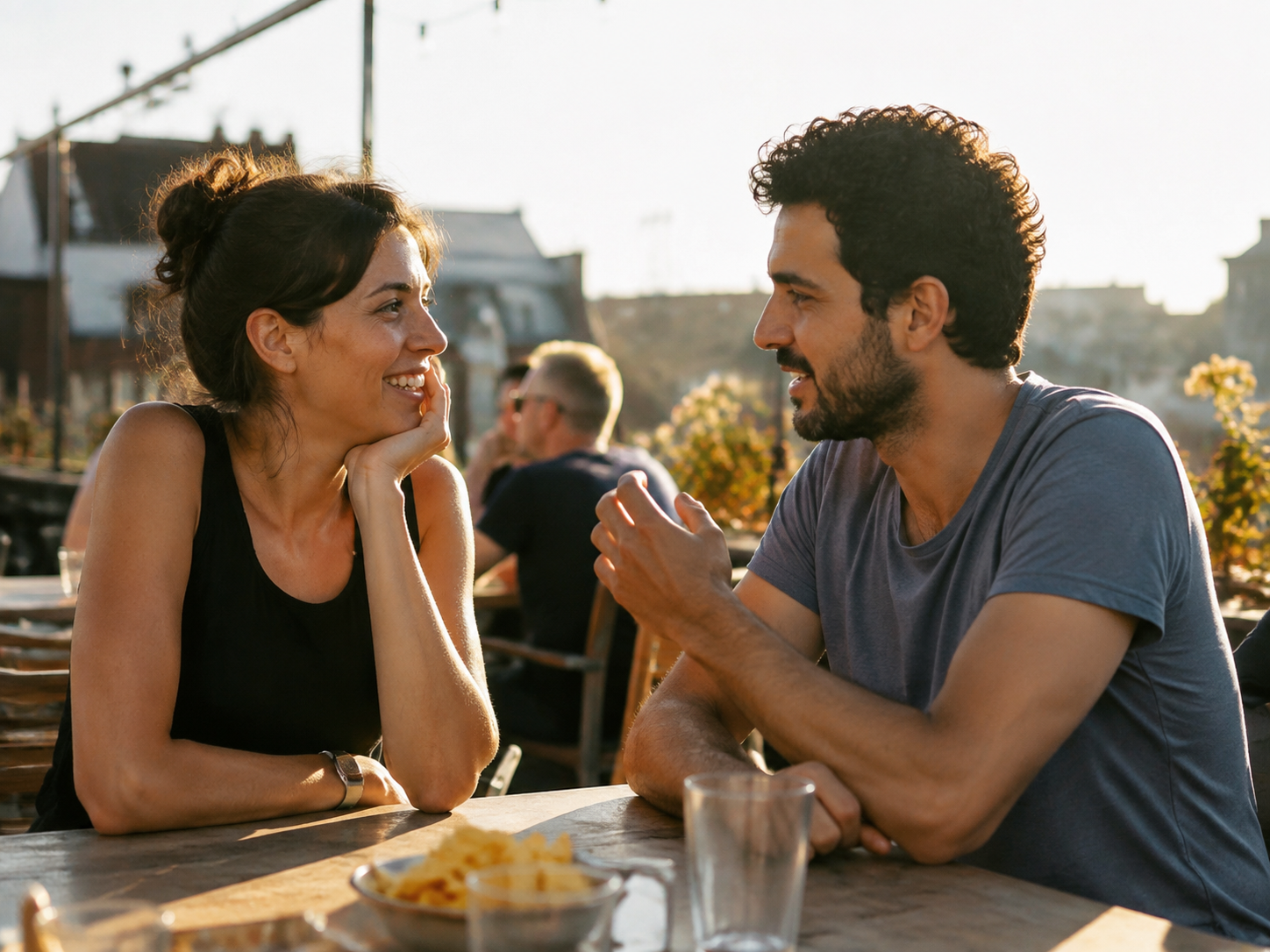Adults talking at a bright rooftop café before sunset