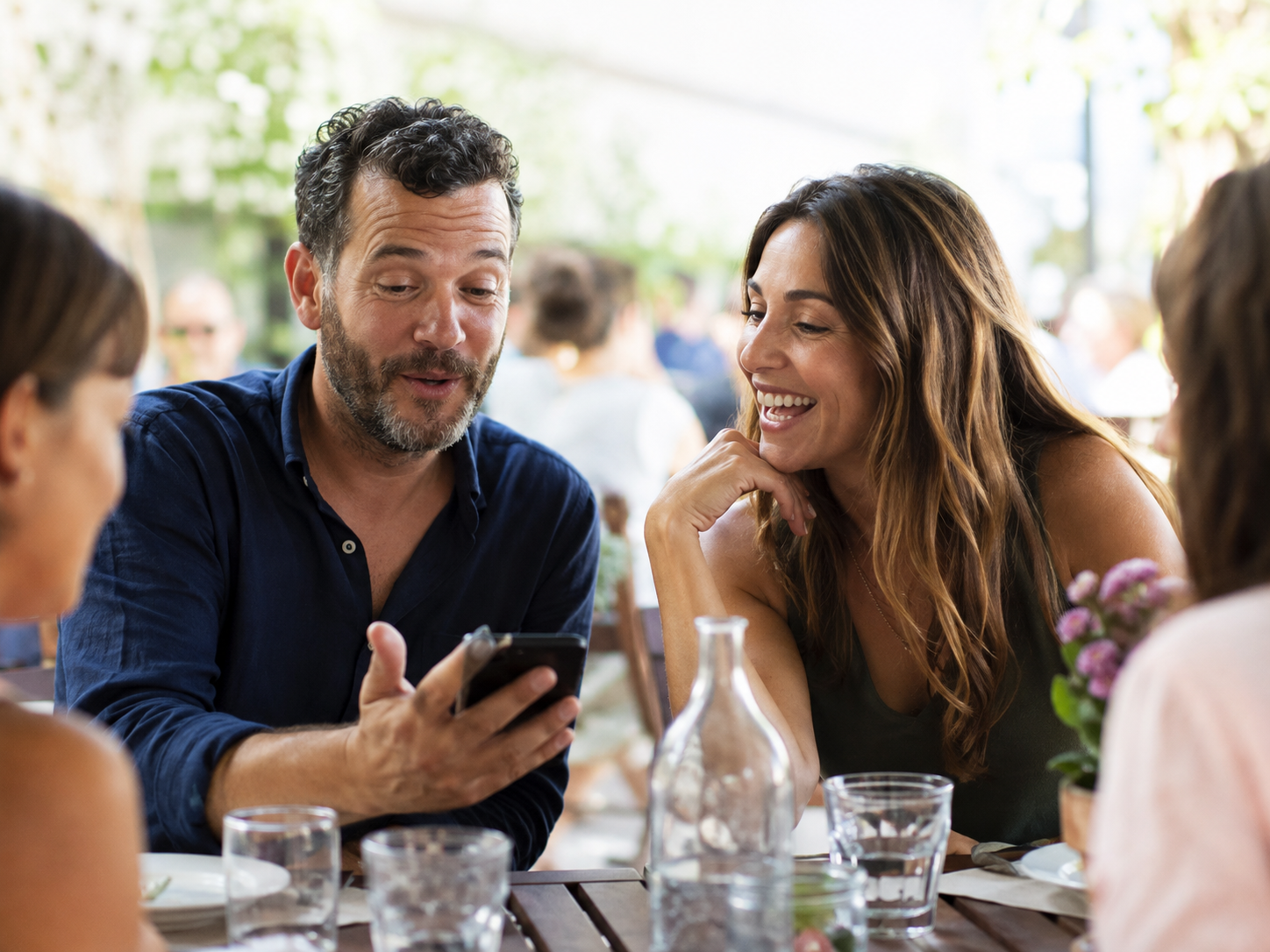 Adults sharing photographs during a daytime public lunch