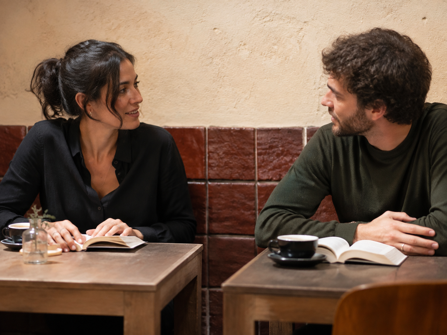 Adults reading at adjacent tables in a quiet café then talking