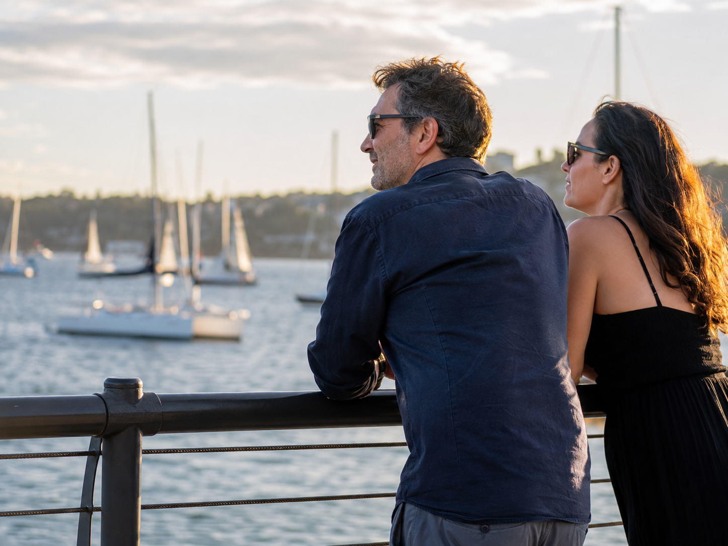 Adults watching boats at a waterfront railing