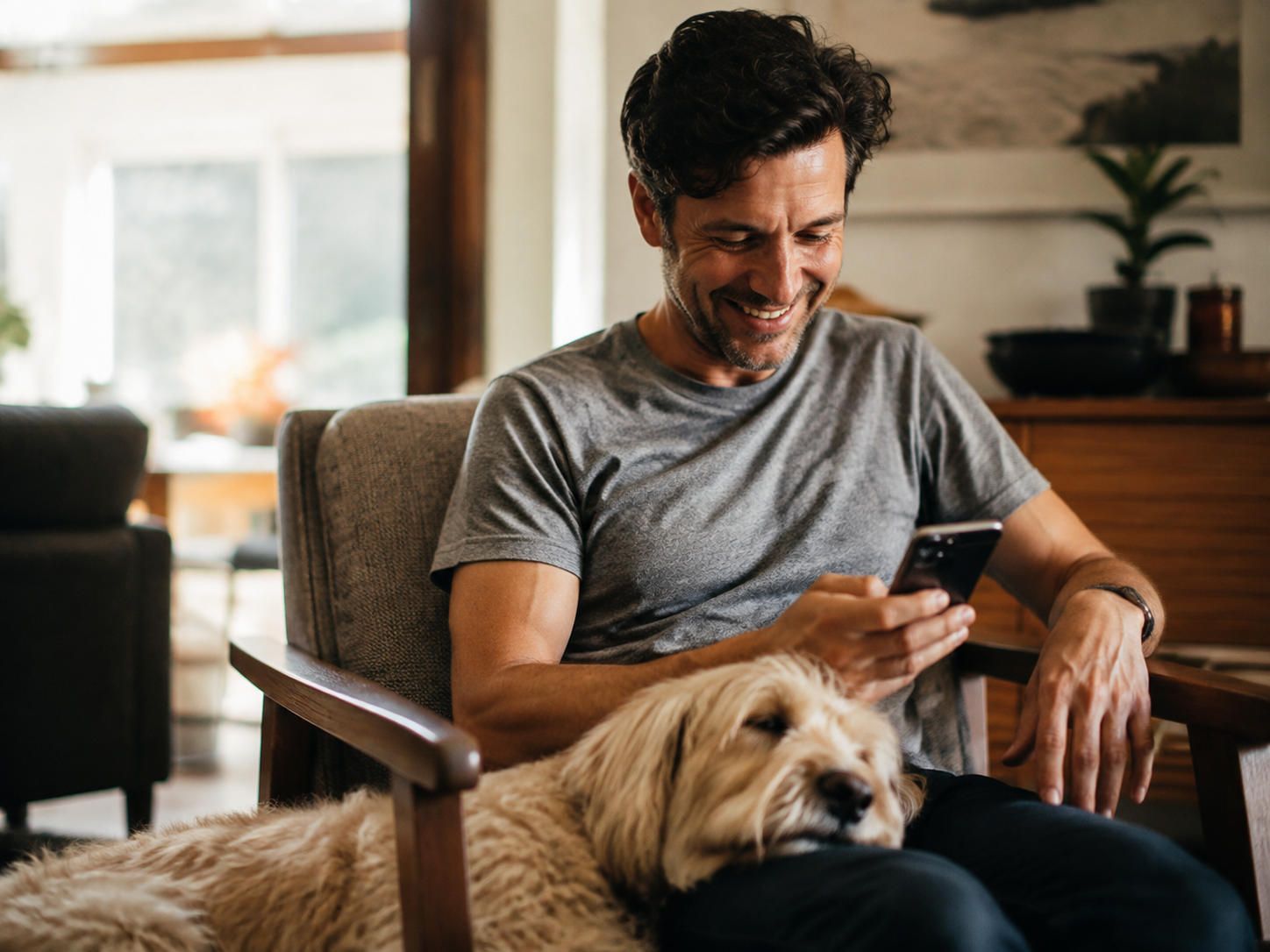 Adult smiling at a message with a dog resting nearby