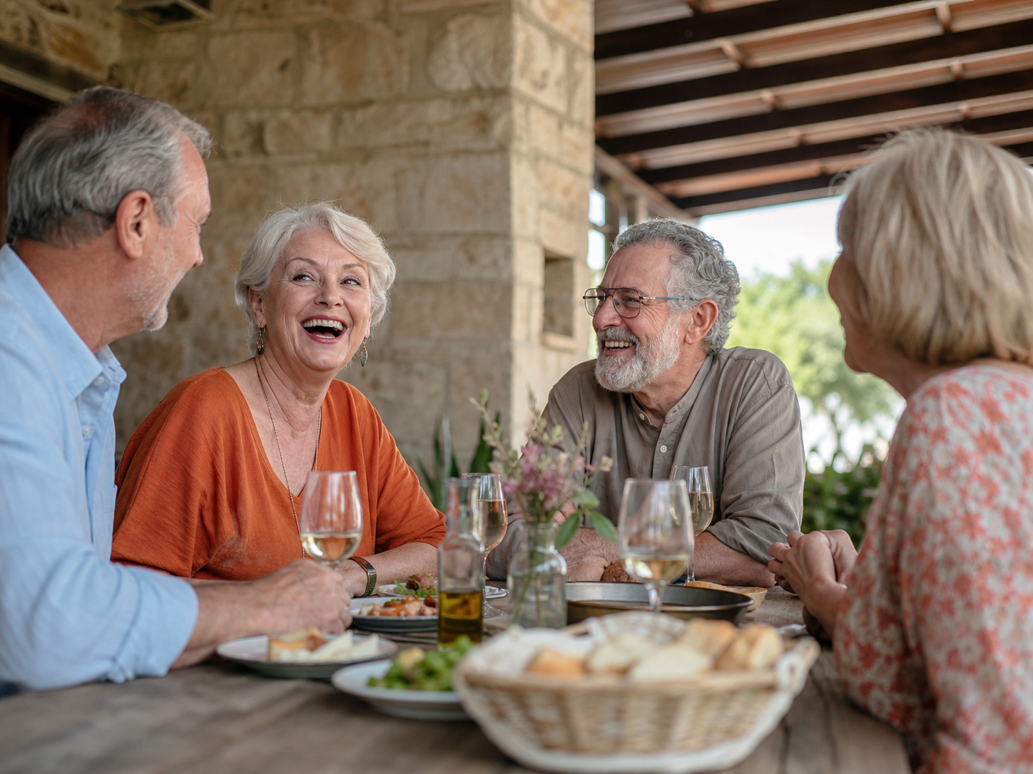 Older adults laughing over lunch on a shaded veranda