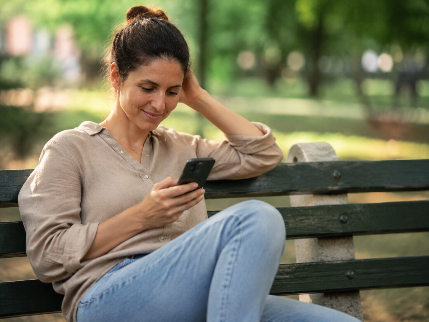 Adult checking a message while resting on a park bench